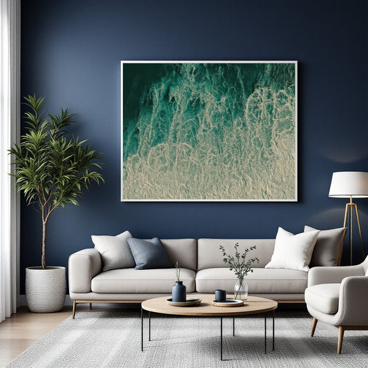 A large framed abstract wall art print with swirling teal, aqua, and cream wave-like patterns hangs above a light gray sofa in a styled living room with a navy blue wall, potted plant, coffee table, and lamp.
