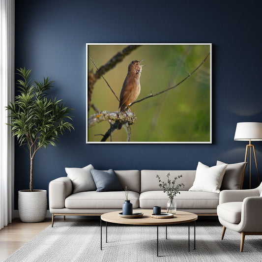 A framed wall art print showing a brown bird perched on a branch against a soft green background, displayed above a light gray sofa in a modern living room with a dark blue wall, potted plant, and coffee table.