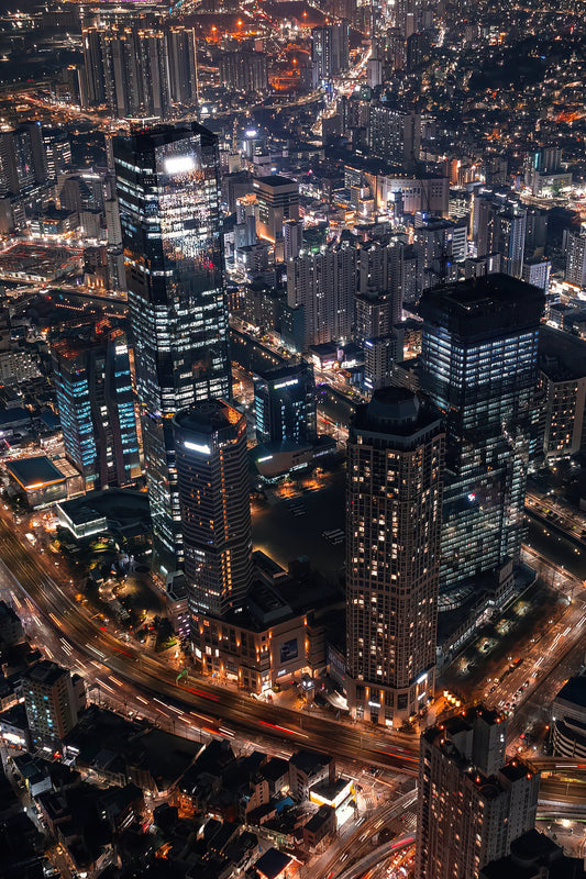 Vertical aerial photograph of illuminated skyscrapers and city lights at night.