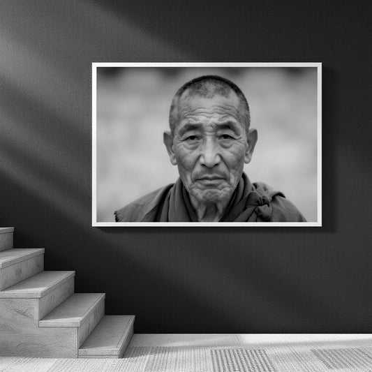 A framed black and white portrait print of an elderly man hanging on a dark wall above a staircase.