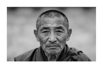 A black and white portrait photograph of an elderly man with a serious expression, framed with a white border.