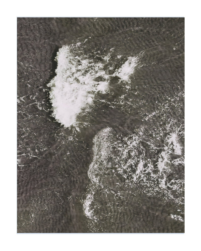 An aerial photograph of dark, textured water with white surf and foam, presented as a square art print with a white border.
