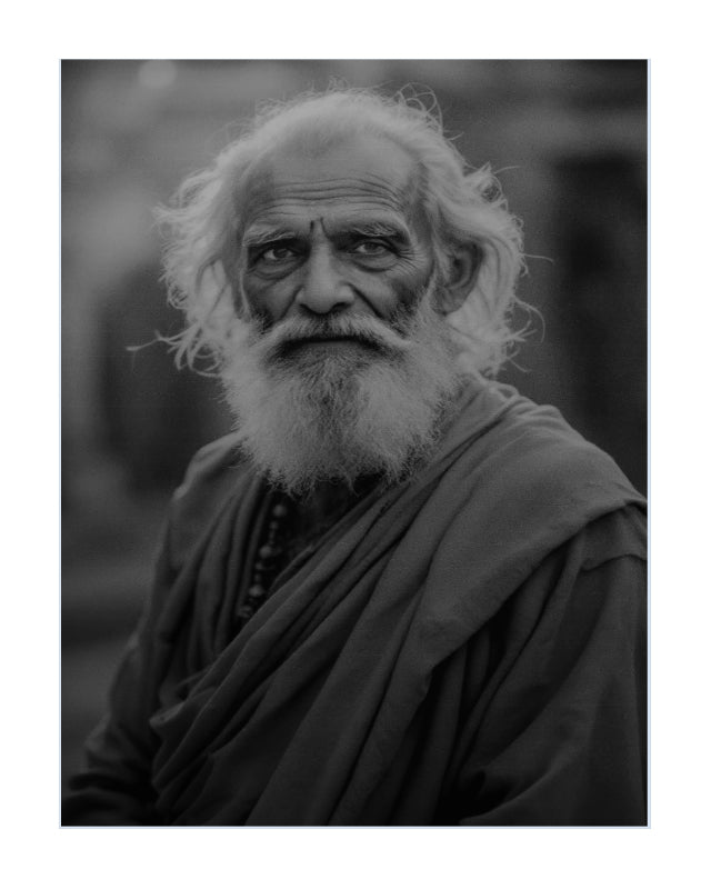 Black and white portrait print of an elderly bearded man with wild white hair, wearing draped robes, shown against a softly blurred dark background.