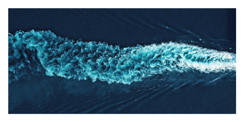 A square abstract photograph of deep blue water with a bright turquoise wave or wake cutting diagonally across the frame.