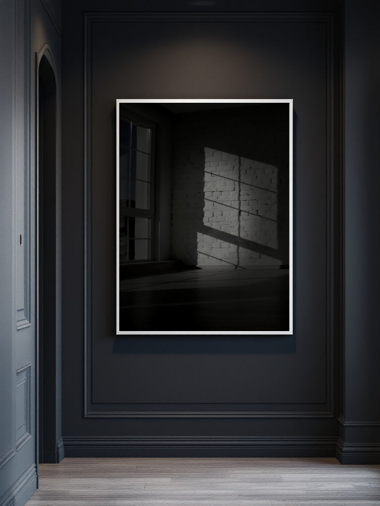 A framed black and white art print depicting a shadow pattern on a wall, displayed on a dark charcoal paneled wall above a light wood floor.