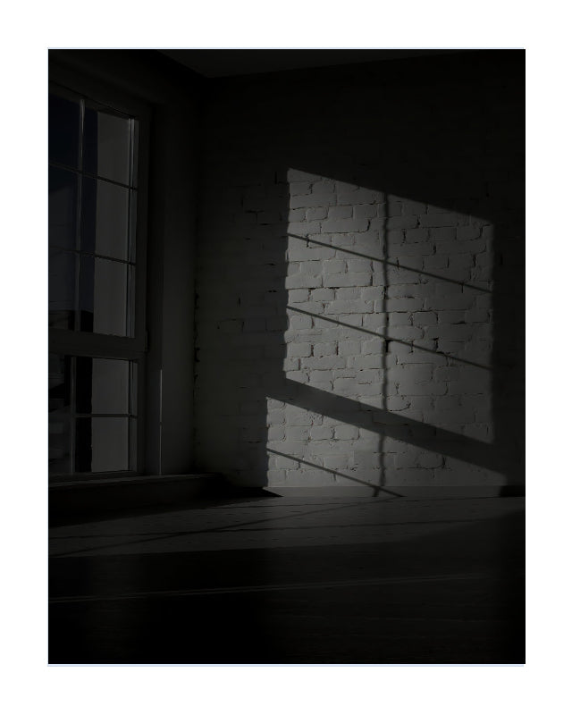 A moody black and white photograph of a room corner with a window casting dramatic light and shadow across a white brick wall and dark floor.