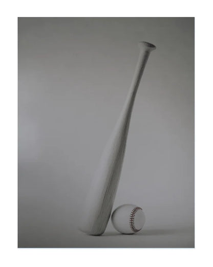 A minimalist studio photograph of a light gray wooden baseball bat leaning against a baseball, set against a matching gray background.