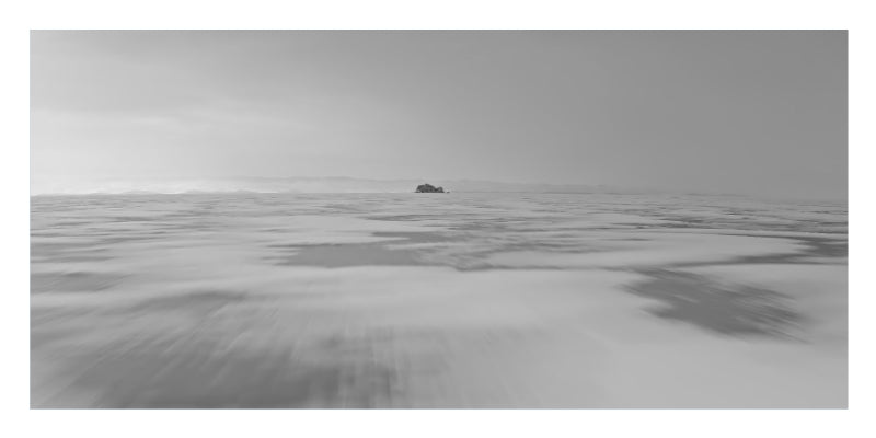 A black and white landscape photograph of a vast, flat horizon with a small dark object in the distance, presented with white borders.