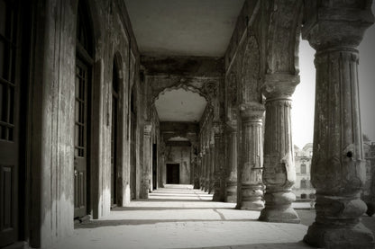 Black and white photograph of an ancient stone colonnade with tall fluted columns and arched passageways receding into the background.