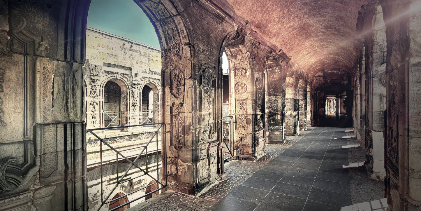 A long stone corridor with arches and carved walls, leading into the distance under a vaulted ceiling in a historic building.