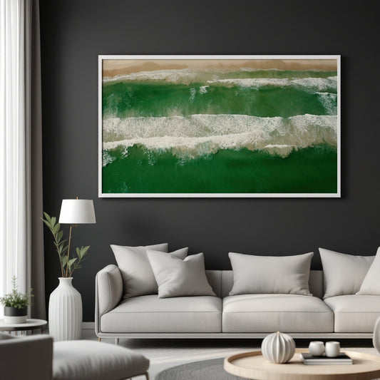 A framed abstract ocean wave painting in shades of green, white, and beige hangs on a dark charcoal wall above a light gray sofa in a modern living room setting.