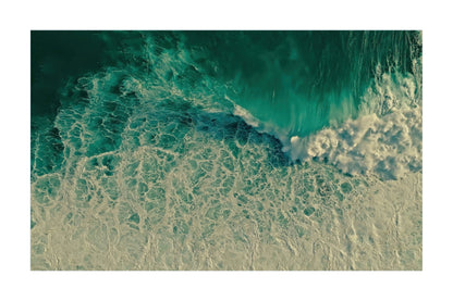 An aerial photograph of ocean waves with turquoise and deep teal water transitioning into white foam, presented as a square art print with a white border.