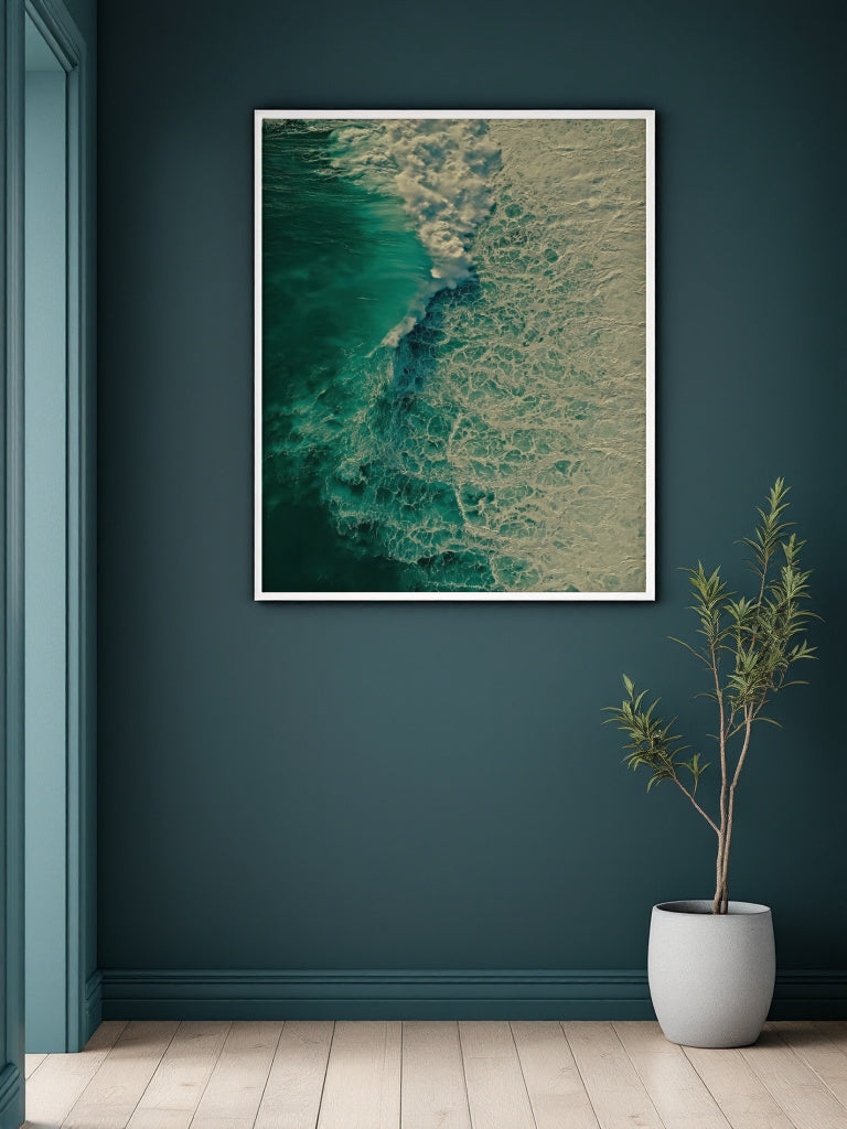 A framed abstract art print depicting a teal and beige wave pattern, displayed on a dark teal wall above a light wood floor next to a potted plant.