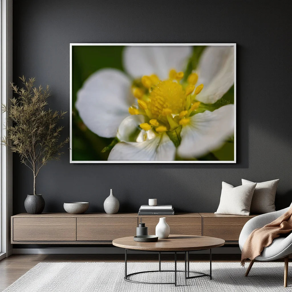 A framed wall art print featuring a close-up of a white flower with a bright yellow center, displayed above a modern wooden console in a styled living room setting.
