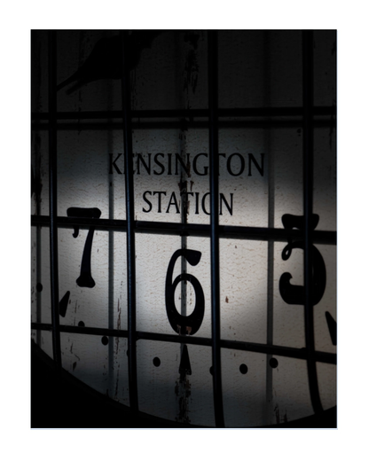A square art print featuring a moody, high-contrast photograph of a vintage clock face at Kensington Station, with the words 'KENSINGTON STATION' and numbers obscured by dark bars and shadows.