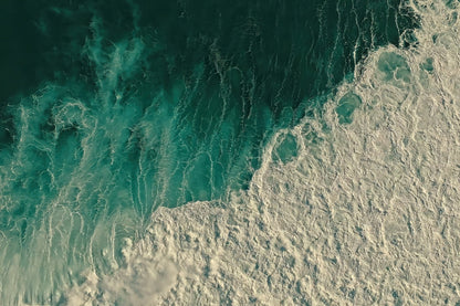 Aerial view of ocean waves with deep teal water transitioning into white sea foam.