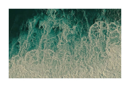 An aerial photograph of ocean waves with swirling turquoise water and white foam, presented as a square art print with a white border.