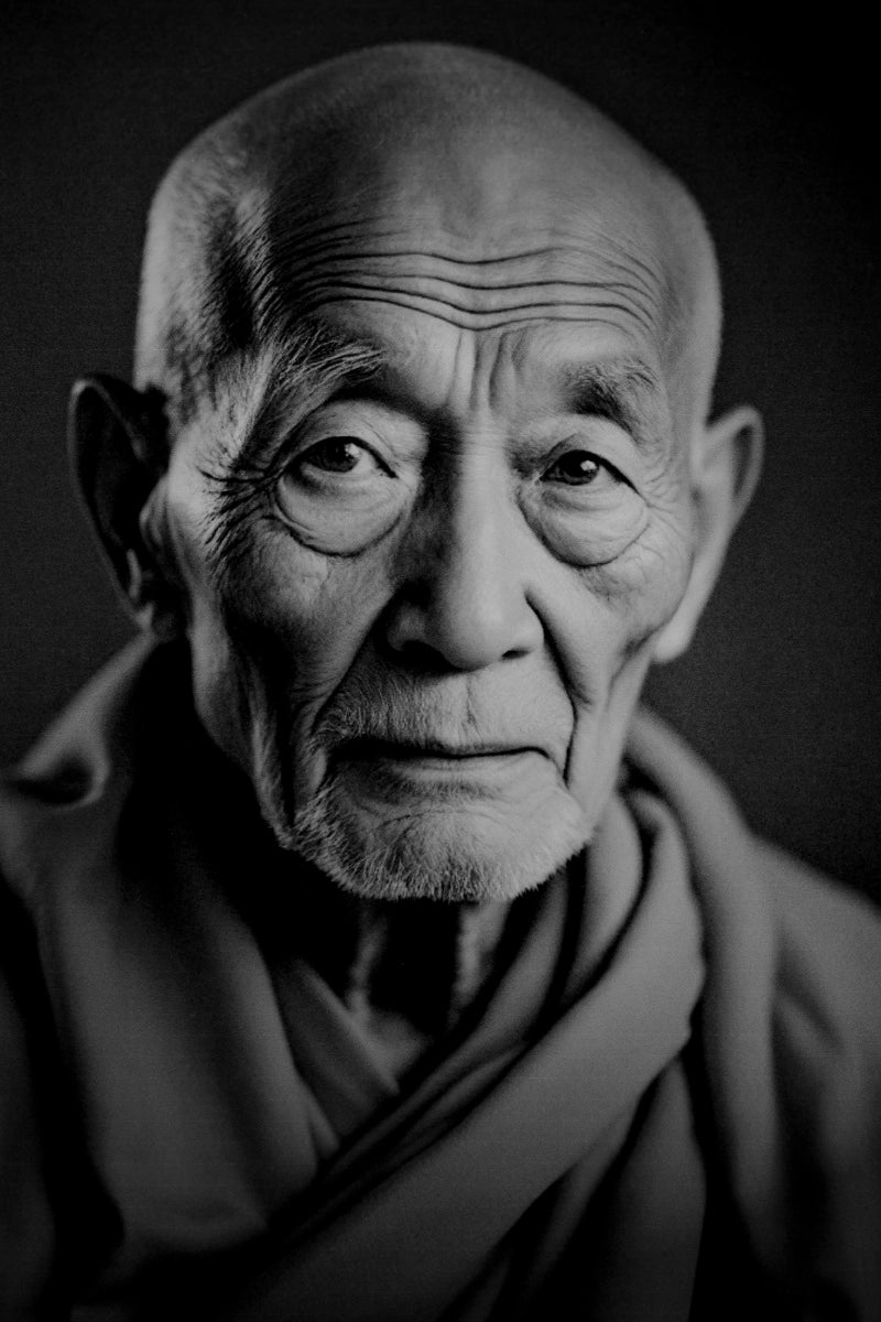 Black and white close-up portrait of an elderly bald man with deep facial wrinkles, wearing draped clothing against a dark background.