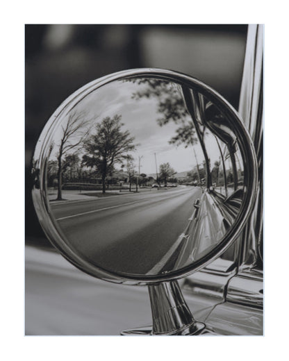 A black and white art print depicting a classic car side-view mirror reflecting a tree-lined road.