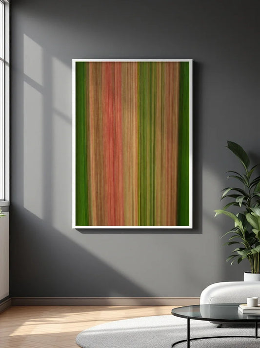 A framed vertical abstract art print with vertical stripes in shades of green, red, and orange, displayed on a dark gray wall in a modern living room setting.