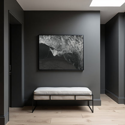 A black and white abstract framed wall art print hangs on a dark gray entryway wall above a light beige upholstered bench with black metal legs, set on light wood flooring.
