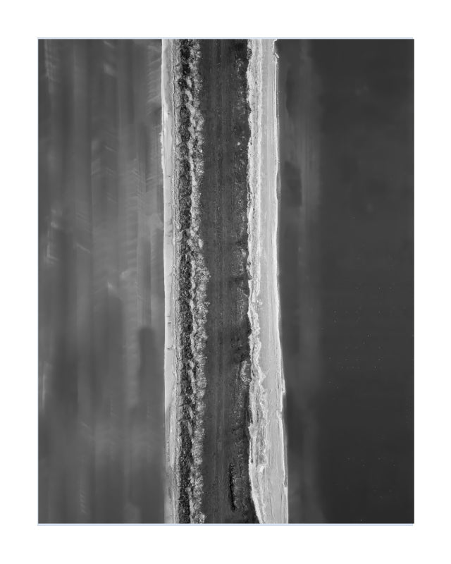 A black and white abstract art print featuring a vertical textured strip of rough, granular material between two smooth dark gray and white backgrounds.