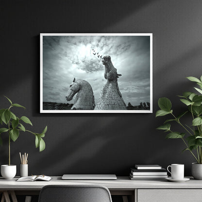 A framed black and white art print depicting the Kullreid Horse statues at Edinburgh, displayed on a dark gray wall above a styled desk with plants and office accessories.