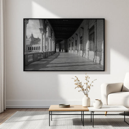 A large black and white framed wall art print depicting a long architectural corridor, displayed on a light wall above a coffee table in a modern living room setting.