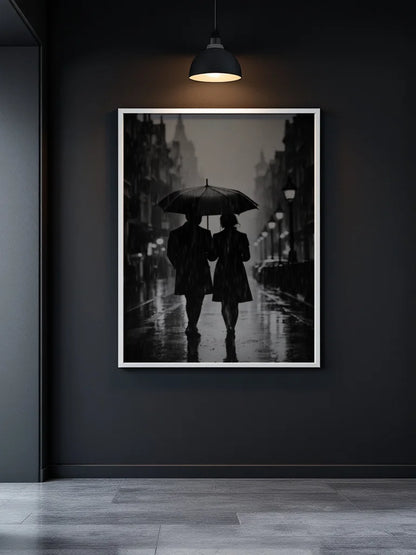 A framed black and white art print depicting a couple under an umbrella on a rainy street, displayed on a dark gray wall under a hanging lamp.