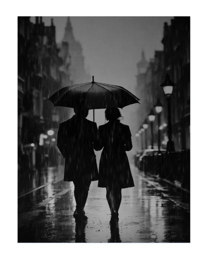 Black and white photograph of a couple walking hand in hand under a large umbrella on a wet city street at night, with rain visible and buildings lining the road.