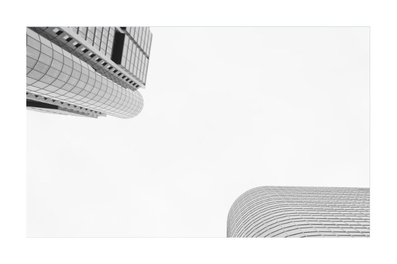 Minimalist black and white architectural photograph featuring two curved modern skyscrapers framing a large blank white space in the center.