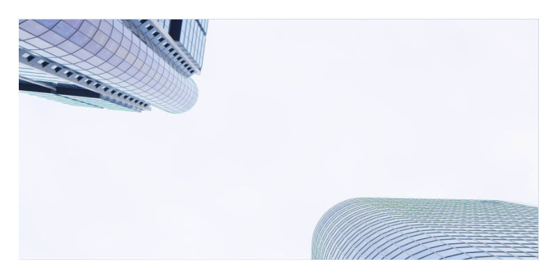 Low-angle architectural photograph of modern glass skyscrapers against a bright white sky, with the tops of two curved buildings visible.