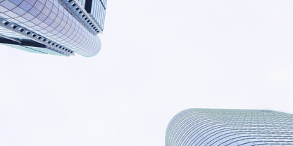 Abstract architectural photograph of modern glass skyscrapers viewed from below against a bright white sky.