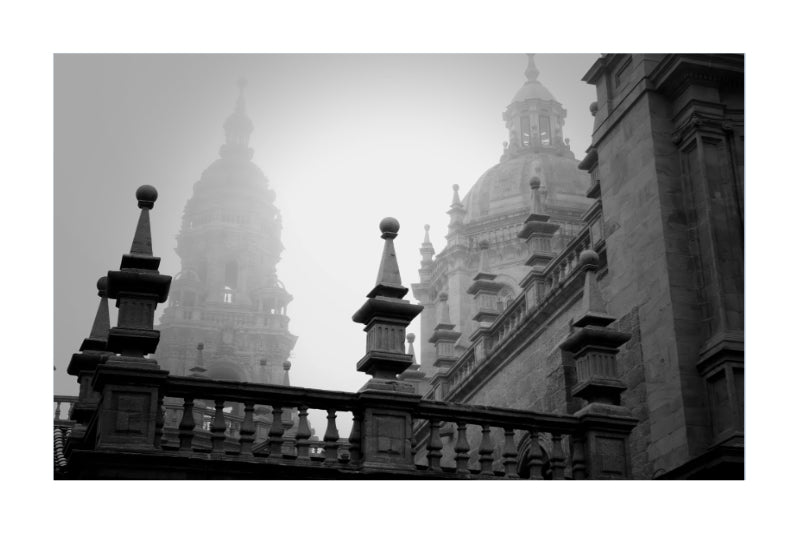 Black and white architectural photograph featuring historic domed buildings behind a stone balustrade in the foreground, presented with a white border.