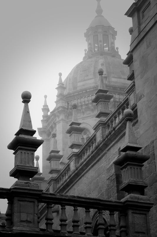 Black and white architectural photograph of a grand domed cathedral or historic building seen through mist, with stone railings and balustrades in the foreground.