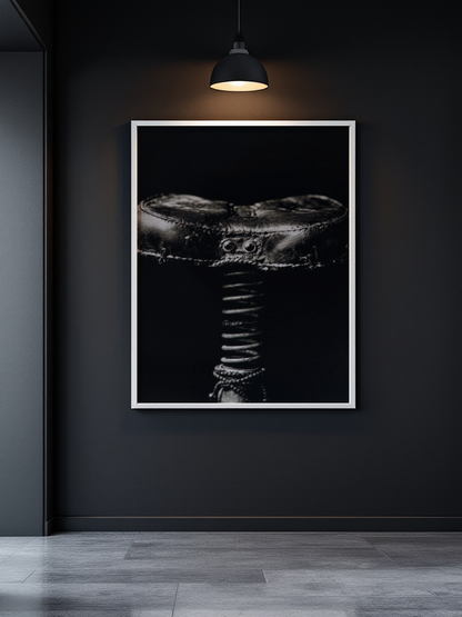 A framed black and white art print of a textured drum head hanging on a dark charcoal wall under a pendant lamp, with gray floor tiles below.