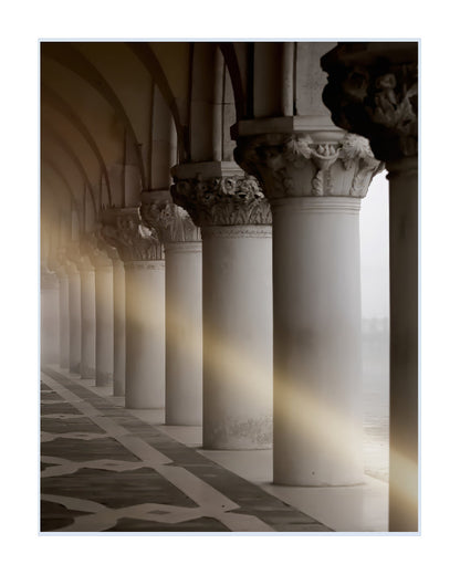 A fine art photograph of a classical colonnade with white stone columns, arches, and a patterned floor, featuring dramatic light rays filtering through.