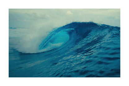 A square art print depicting a powerful blue ocean wave curling under a cloudy sky, presented with a white border.