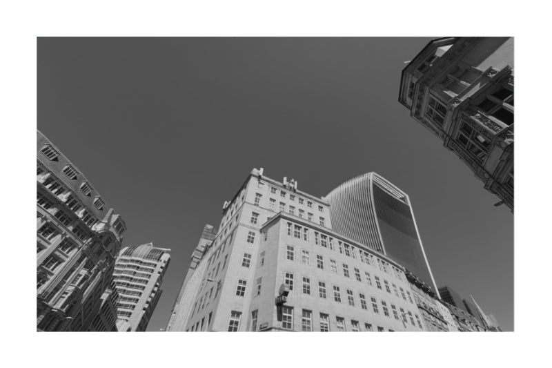Black and white architectural photograph of city skyscrapers, featuring a low-angle perspective looking up at modern buildings against a dark sky.