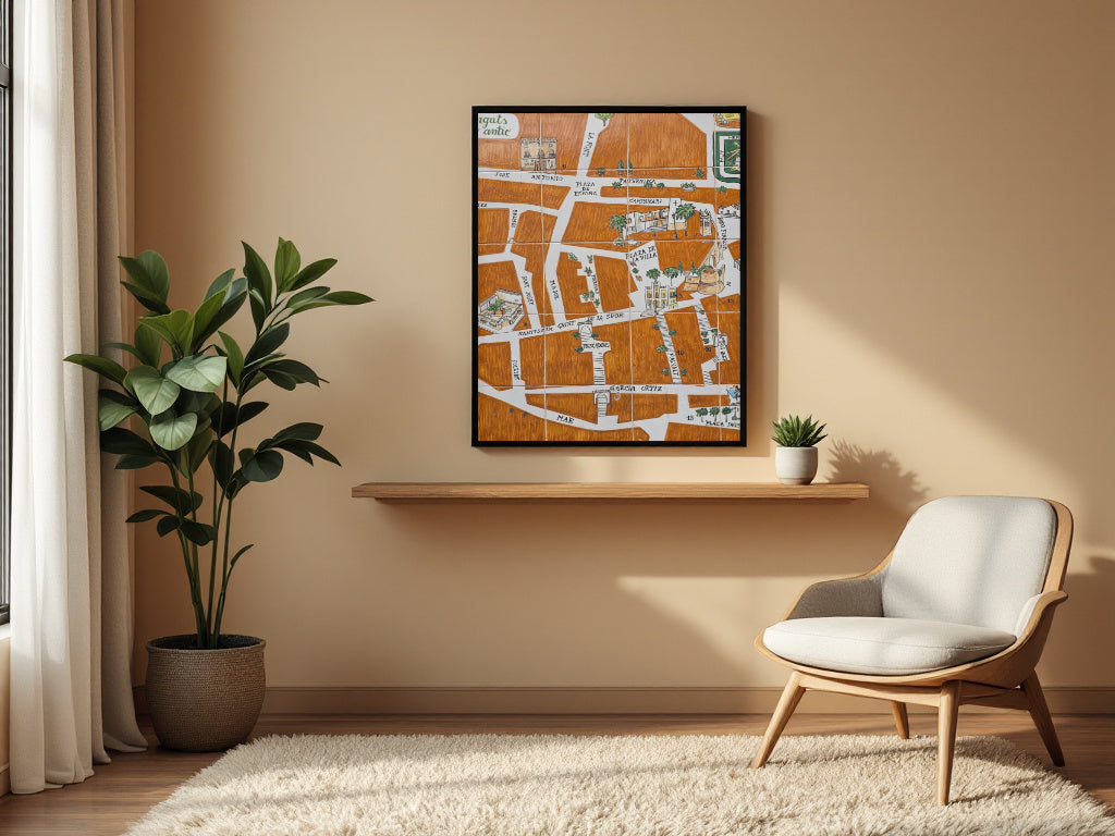 A framed art print featuring an orange and white street map design hangs on a beige wall in a modern living room setting above a wooden floating shelf, next to a green potted plant and a light wood armchair.