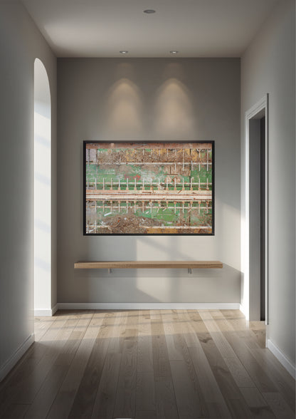 A framed abstract landscape art print with green, brown, and beige tones, displayed on a gray wall in a modern hallway with a light wood floating shelf below it.