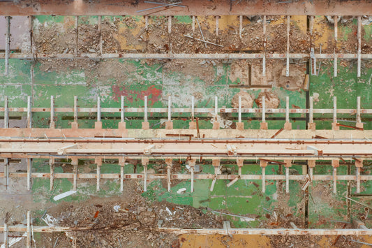 A close-up view of a weathered green and beige industrial wall and machinery panel with rusted metal, wooden beams, and debris.