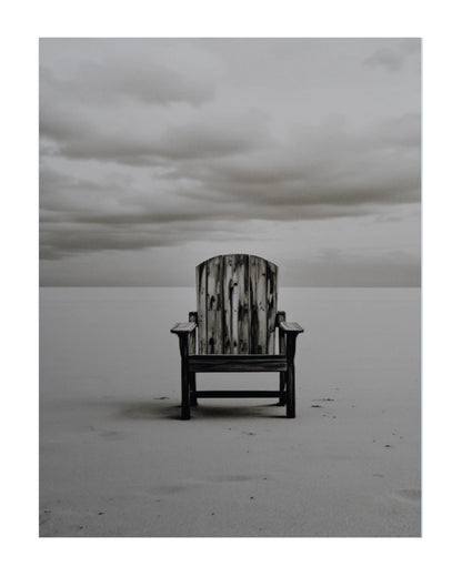 A weathered wooden Adirondack chair sits alone on a flat, pale beach under a cloudy gray sky.
