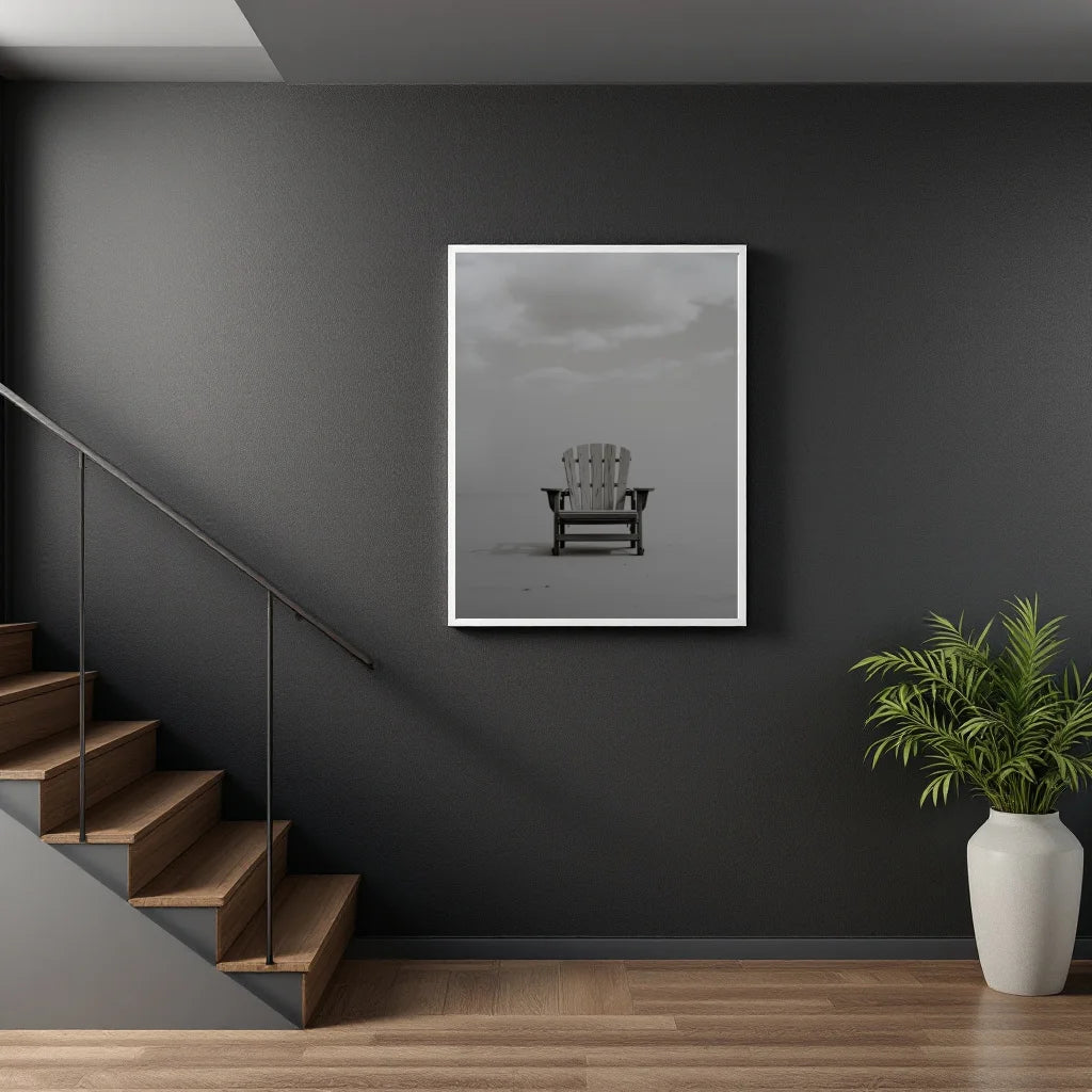 A framed black and white art print of an Adirondack chair hanging on a dark gray wall in a modern interior setting with wooden stairs and a potted plant.