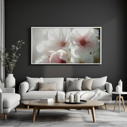 A large framed wall art print featuring soft white and pink flowers, displayed above a light gray sofa in a modern living room setting.