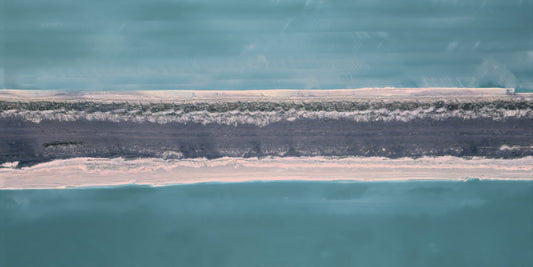 Aerial abstract representation of a narrow strip of pale sand and dark vegetation between two large areas of turquoise water.