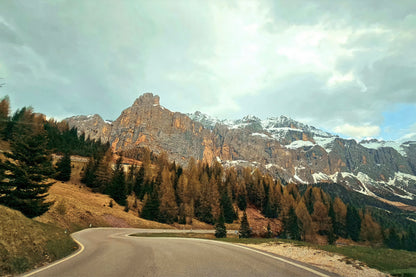Road going through the Dolomites mountains. The scenic road shows the rocky mountains dusted in some snow.