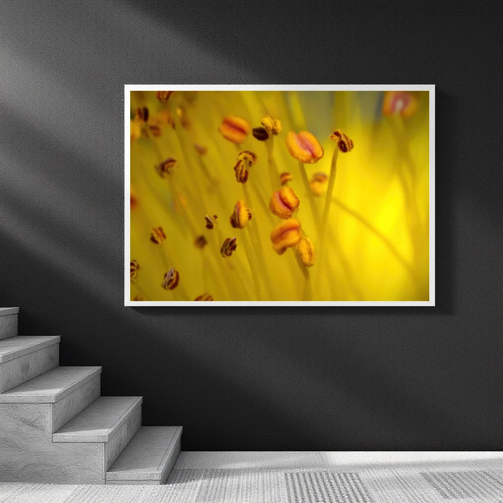 A framed wall art print showing a close-up yellow floral scene with small orange-brown flower buds, displayed on a dark gray wall above a staircase.