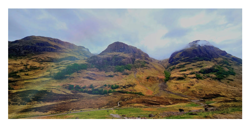 Three rugged Highland peaks rise above a green valley beneath a moody sky in a photo mount