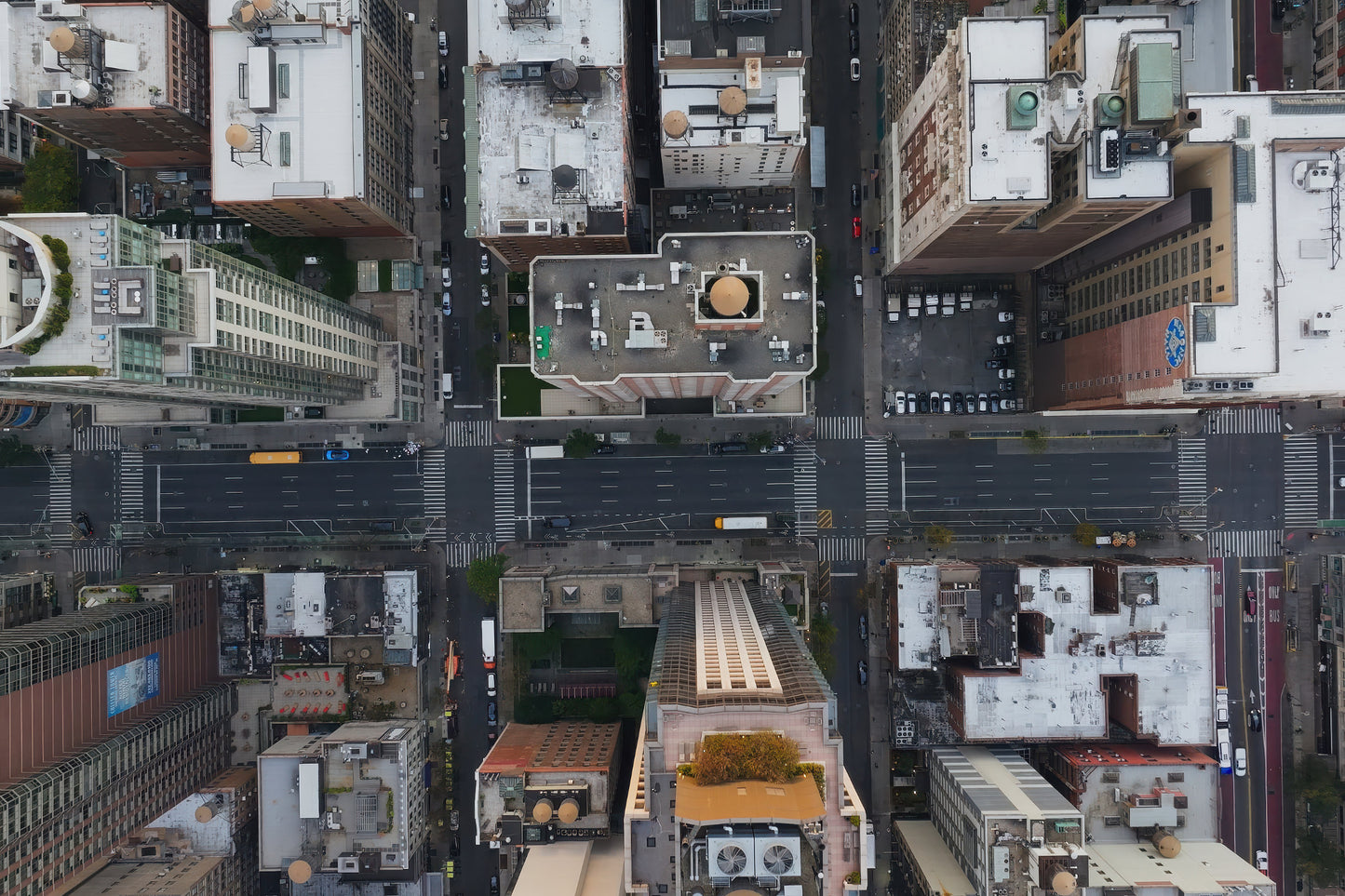 Aerial top-down photograph of a dense city street grid with surrounding buildings, roads, crosswalks, and rooftops.